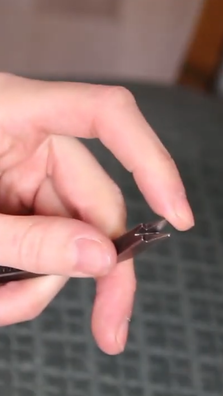 Gros plan sur un arrache-agrafes utilisé pour retirer des clous d’un fauteuil Voltaire. 