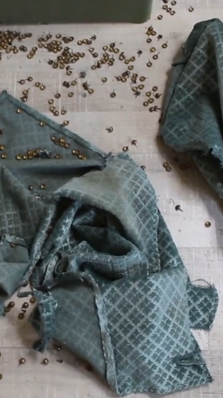 Clous et tissu retirés d'un fauteuil voltaire éparpillés partout sur le sol