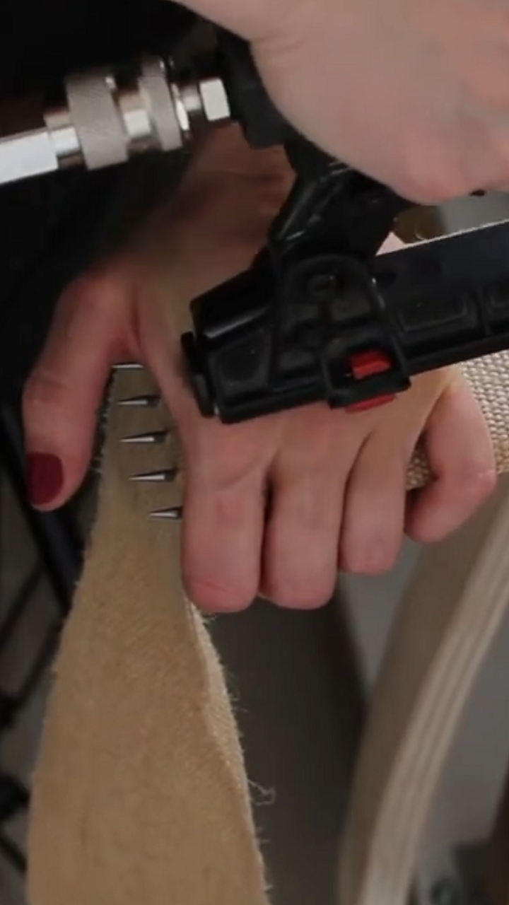 Démonstration de l’utilisation d’un tire-sangles pour tendre une sangle en jute sur une chaise en cours de restauration. Explication du fonctionnement de l’outil et de son importance pour obtenir une bonne tension