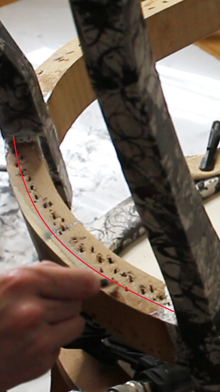 Gros plan sur un repère tracé aux 2/3 sur la traverse d’un fauteuil en cours de sanglage. Explication de l’importance de bien positionner les sangles pour éviter d’abîmer la structure du siège et garantir sa solidité.